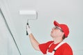 Painter worker with roller painting ceiling surface into white Royalty Free Stock Photo