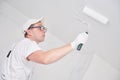 Painter worker with roller painting ceiling surface into white Royalty Free Stock Photo