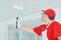 Painter worker with roller painting ceiling surface into white Royalty Free Stock Photo