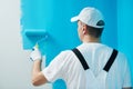 Painter worker with roller painting wall surface into color