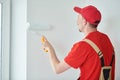 Painter worker with roller painting wall surface into white Royalty Free Stock Photo