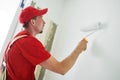 Painter worker with roller painting wall surface into white Royalty Free Stock Photo