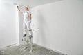 Painter worker on stilts with roller painting ceiling into white Royalty Free Stock Photo