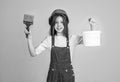 painter in workshop. renovation and repair. teen girl in helmet and boilersuit with painting brush and bucket. child