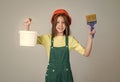 painter in workshop. renovation and repair. teen girl in helmet and boilersuit with painting brush and bucket. child