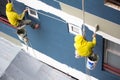 Painters hanging on roll, painting color on building wall Royalty Free Stock Photo