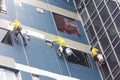 Painters hanging on roll, painting color on building wall. Royalty Free Stock Photo