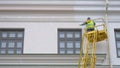 Painters standing on Aerial ladder paint the wall on construction site