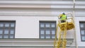 Painters standing on Aerial ladder paint the wall on construction site