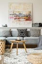 Painting above grey couch in boho living room interior with wood Royalty Free Stock Photo