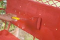 Painting the back rest of an old glider swing made of wrought iron with red oxide primer paint. Using a small paint roller. Royalty Free Stock Photo