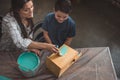 Little son and his beautiful mother painting a wooden birdhouse while sitting