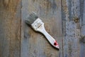 Painting brush in white paint dye is lying on the wooden background. Realistic grey and brown vintage surface. Shaggy and grained Royalty Free Stock Photo