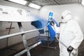 Painting the bumper of car in the paint room, spray gun with white paint.