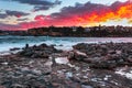 A painting of burning clouds and the sea and rocks