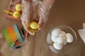 Painting chicken eggs for Easter in yellow. A girl in transparent disposable gloves paints eggs in the color of the year, yellow.
