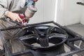 Painting the element body of the car - the aluminum alloy wheel with the help of aerograf in black color by the hand of painter Royalty Free Stock Photo