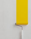 Painting empty wall in yellow with paint roller.Concept for colour advertising.