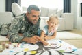 Military servant and his daughter painting family tree together