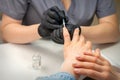 Painting female nails. Hands of manicurist in black gloves is applying transparent nail polish on female nails in a Royalty Free Stock Photo