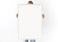 Painting frame mockup. Woman holds a big vertical white picture frame. Copy space for your logo Royalty Free Stock Photo