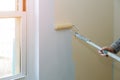 Male hand painting wall with paint roller. Painting apartment, renovating with color paint