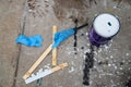 Painting mess - a can of white paint sits on messy dropcloth with white and black paint surrounded by opener and stir sticks and r