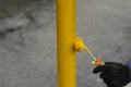 Painting a metal post with yellow paint. Parking bollard painting Royalty Free Stock Photo