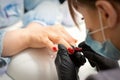 Painting nails of a woman. Hands of Manicurist in black gloves applying red nail polish on female Nails in a beauty Royalty Free Stock Photo