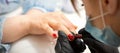 Painting nails of a woman. Hands of Manicurist in black gloves applying red nail polish on female Nails in a beauty Royalty Free Stock Photo