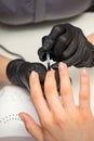 Painting nails of a woman. Hands of Manicurist in black gloves applying transparent nail polish on female Nails in a Royalty Free Stock Photo