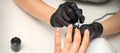 Painting nails of a woman. Hands of Manicurist in black gloves applying transparent nail polish on female Nails in a Royalty Free Stock Photo