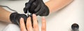 Painting nails of a woman. Hands of Manicurist in black gloves applying transparent nail polish on female Nails in a Royalty Free Stock Photo