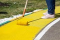 Painting objects in the park in yellow. Yellow oil paint. Work of the park improvement worker. Brush with yellow paint on a pile.