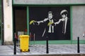 Painting of Pulp Fiction movie characters aiming at a yellow trash bin with bananas