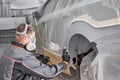 Painting the rear part of the car. Car painter wearing costume and protective gear. Car service station. Restoring a car Royalty Free Stock Photo