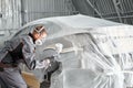 Painting the rear part of the car. Car painter wearing costume and protective gear. Car service station. Restoring a car Royalty Free Stock Photo