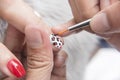 Painting red and black leopart spots onto a polished finger nail with a very fine brush. Nail art procedure and finishing touches