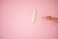 Painting and renovation. A hand holding a paint roller against the pink background newly painted. Soft focus on the laborpi`s hand