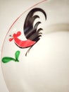 painting of a rooster on a ceramic plate and green leaves