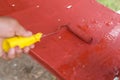 Painting the seat of an old glider swing made of wrought iron with red oxide primer paint. Using a small paint roller. Restoring Royalty Free Stock Photo