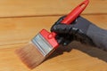 Painting or staining wooden terrace floor. Red brush, close-up