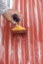 Painting the surface of a sheet of Galvanized Iron or GI corrugated metal with rust inhibiting red oxide primer Royalty Free Stock Photo