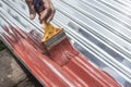 Painting the surface of a sheet of Galvanized Iron or GI corrugated metal with rust inhibiting red oxide primer Royalty Free Stock Photo