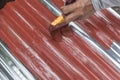 Painting the surface of a sheet of Galvanized Iron or GI corrugated metal with rust inhibiting red oxide primer Royalty Free Stock Photo