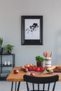 Painting on a wall and dining table with apples, tomatoes and wooden utensils in a dining room interior Royalty Free Stock Photo