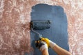 Painting the wall with a roller gray paint. master paints in yellow work gloves. repairs painting tools Royalty Free Stock Photo