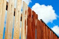 Painting wooden fence with brown paint. Blue sky background