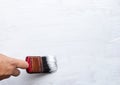 Painting work. Woman paints a wooden surface wall with white acrylic paint. Female hand with brush. Royalty Free Stock Photo