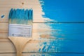 Painting works background with paintbrush in blue paint on the wooden not completely painted boards Royalty Free Stock Photo